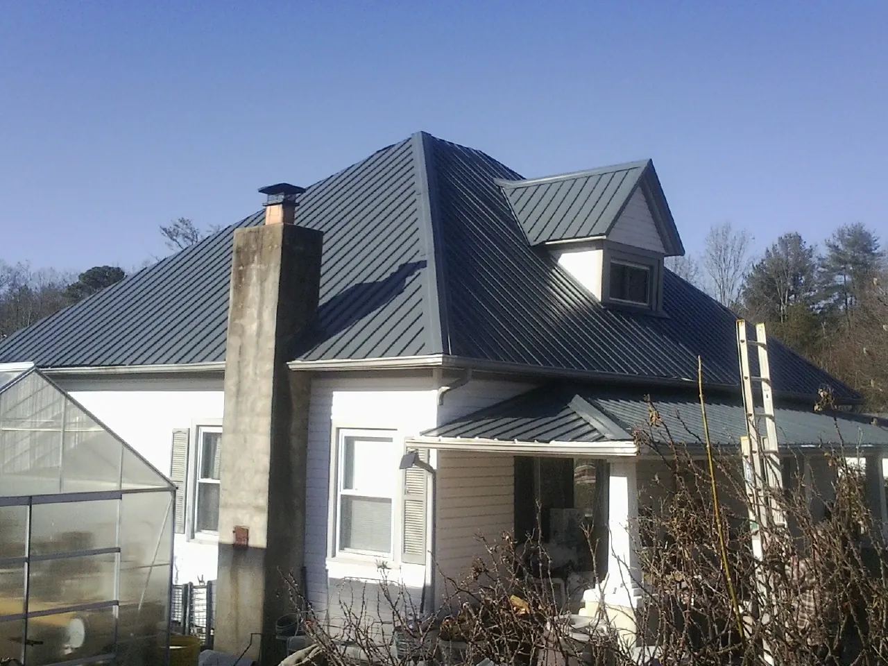 Dark blue standing seam metal roof on a white farmhouse with dormer — Slate & Tile Roof Repair by Roofing Brothers in New Cumberland