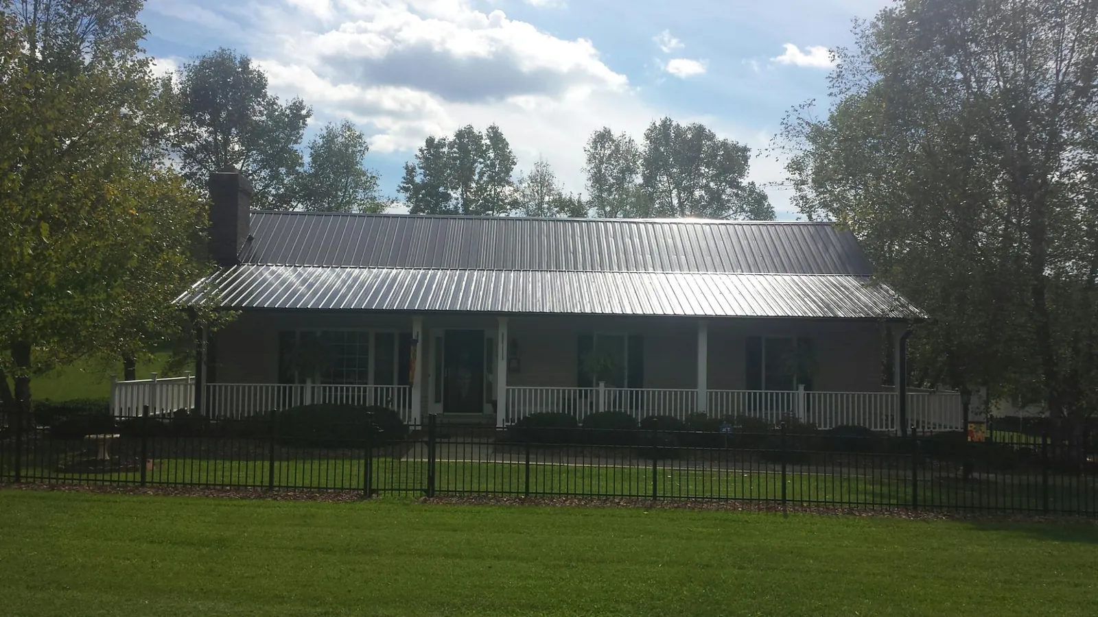 Gray metal roof on a brick ranch with a full width front porch — Gutter Guard Installation work by our crew in New Cumberland
