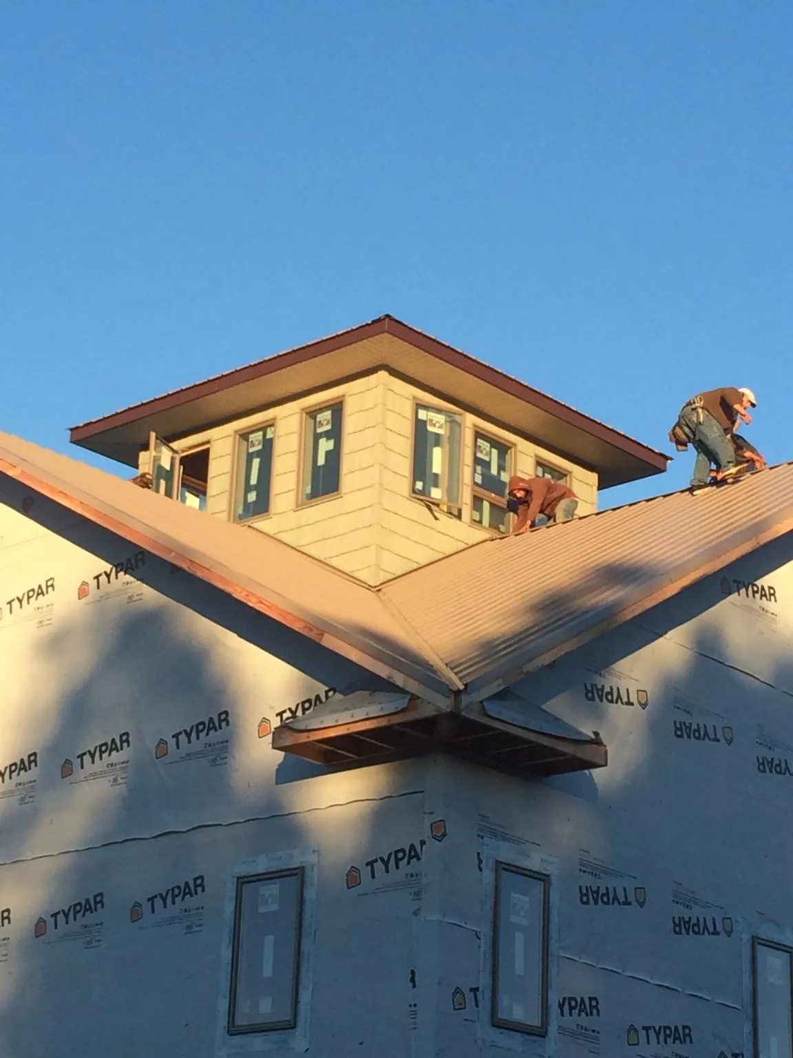 Roofers working around a rooftop cupola on a new metal roof at sunset — Roof Waterproofing in New Cumberland by Roofing Brothers